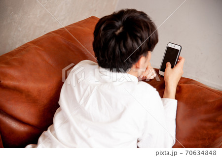 部屋でスマホをみる男性 70634848