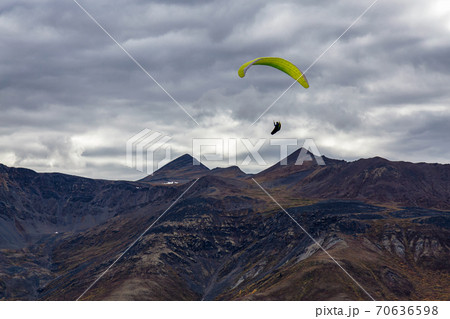 Paraglider flying over Scenic Mountain Range in Canadian Nature Paraglider flying over Scenic Mountain Range in Canadian Nature 70636598
