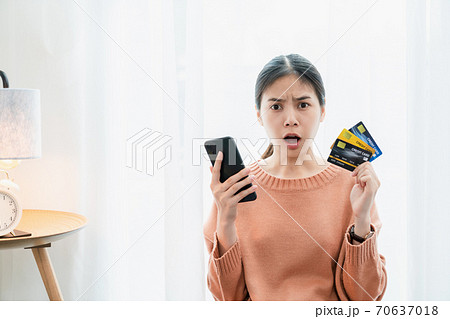 Shocked excited Asian woman holding credit card and smartphone, Because a lot of expenses. 70637018