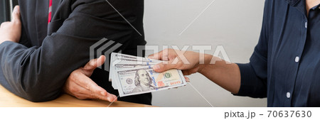 Businessman reciving money United States Dollars bills to corruption from his partner in business at working desk - bribery concept. Businessman reciving money United States Dollars bills to corruption from his partner in business at working desk - bribery concept. 70637630
