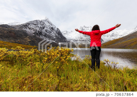 Woman standing with Arms up at Beautifil Alpine Lake 70637864