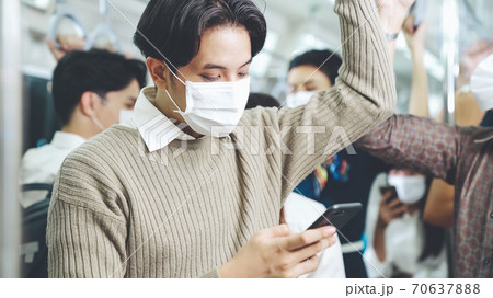 Traveler wearing face mask while using mobile phone on public train 70637888