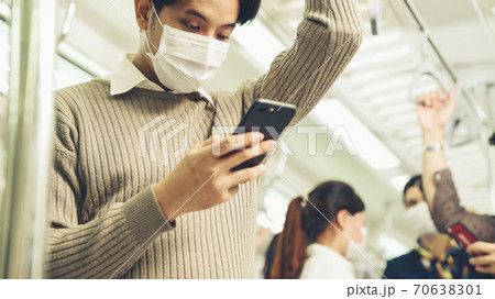 Traveler wearing face mask while using mobile phone on public train Traveler wearing face mask while using mobile phone on public train 70638301