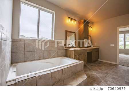 Built in bathtub in front the window of a bathroom with tiled floor and wall Built in bathtub in front the window of a bathroom with tiled floor and wall 70640975