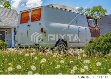 Old van parked in front of a home under blue sky with clouds on a sunny day 70641248
