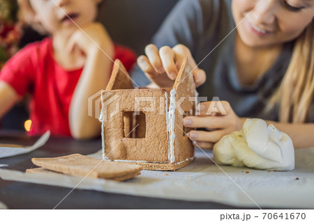 Young mother and kid making gingerbread house on Christmas eve Young mother and kid making gingerbread house on Christmas eve 70641670