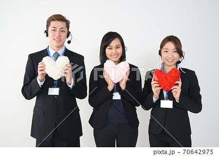 ハートを持ったスーツ姿の若い女性・男性オペレーター3人（上半身） 70642975