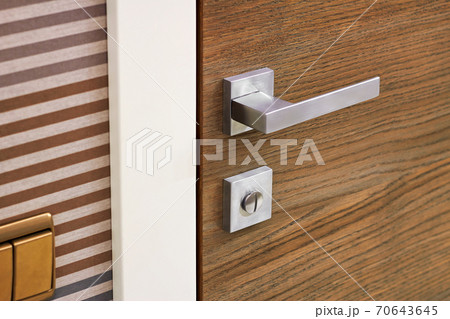 Modern metal door handle on wooden door texture Modern metal door handle on wooden door texture 70643645