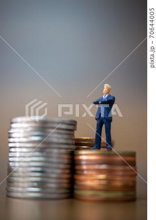 Miniature people: Small businessmen standing with stack of coins  70644005