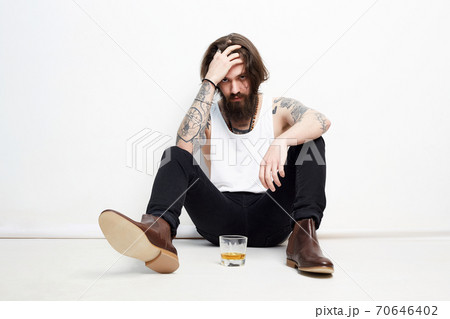 drunk man with beard and tattoo drinking whiskey 70646402
