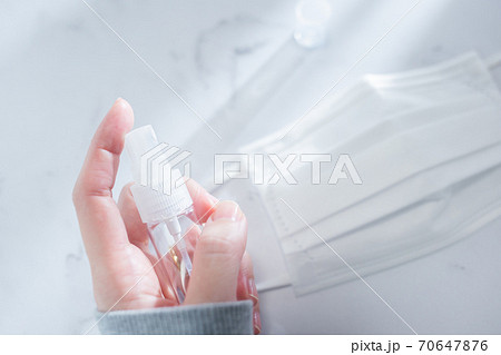 部屋で携帯用の消毒液スプレーを手で持つ様子。 70647876