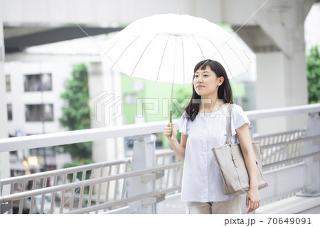 傘をさして街を歩く女性 70649091