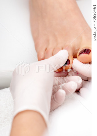 Manicure master holds female toenail Manicure master holds female toenail 70650461