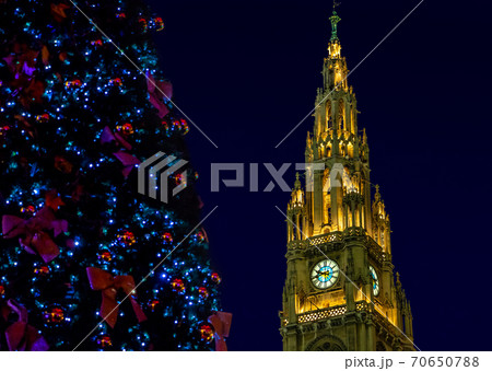 Christmas tree with The illuminated clock tower of city hall - rathaus in Vienna at night, Austria. 70650788