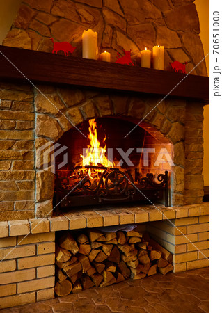 Warm cozy fireplace with real wood burning in it. Cozy winter concept. Christmas and travel background with space for your text. 70651000