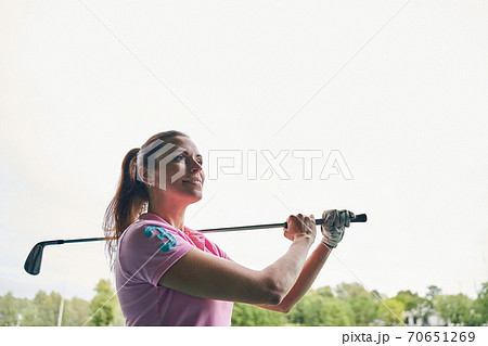 Cheerful sportswoman dressed in a polo shirt gazing away Cheerful sportswoman dressed in a polo shirt gazing away 70651269