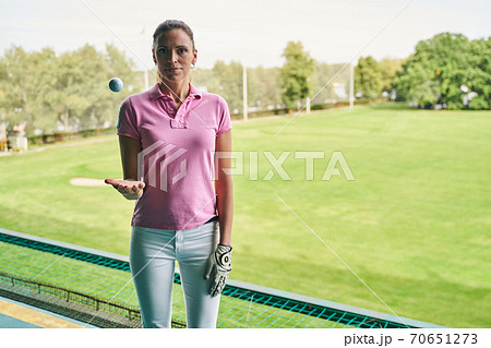Serene female golfer standing in front of the camera Serene female golfer standing in front of the camera 70651273