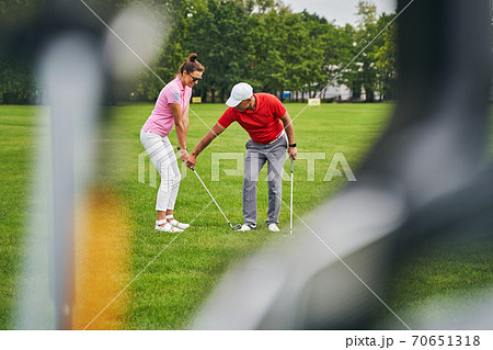 Smiling beginner golfer training with her personal coach Smiling beginner golfer training with her personal coach 70651318