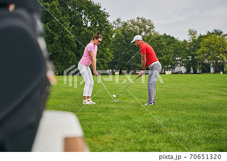 Two adult players perfecting their golf grips Two adult players perfecting their golf grips 70651320