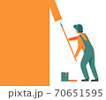 Man in overalls, working uniform with a roller paints, repaints the wall in orange color. 70651595