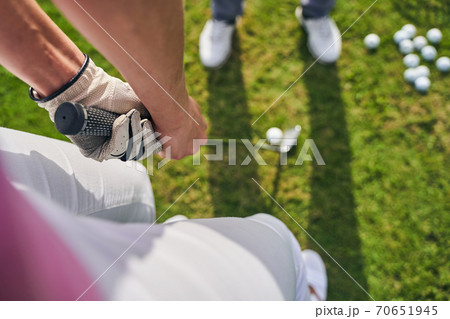 Sportswoman holding a golf putter with both hands Sportswoman holding a golf putter with both hands 70651945