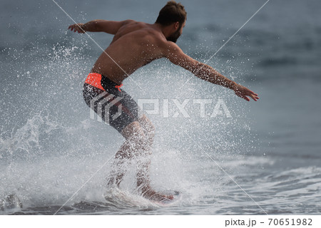 View of a surfer in surfing his board or skimboarding in shallow water 70651982