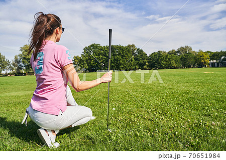Caucasian female golfer with a ponytail sitting on her haunches 70651984