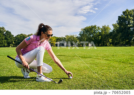 Smiling golfer in sunglasses preparing for a game 70652005