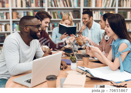 Students sit at a table and chatting together. 70655867