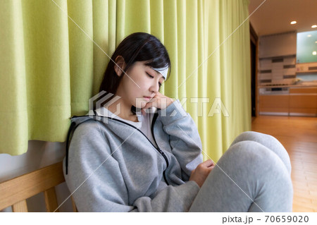 体調不良で欠勤の連絡をする女性 体調不良で欠勤の連絡をする女性 70659020