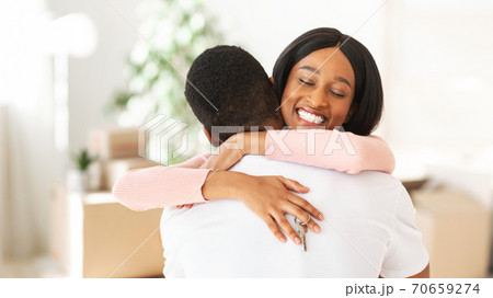 Happy black lady holding house key and embracing her boyfriend in their apartment, copy space Happy black lady holding house key and embracing her boyfriend in their apartment, copy space 70659274