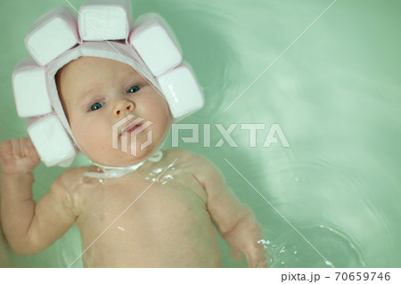 baby bathes in bath in special cap. baby bathes in bath in special cap. 70659746