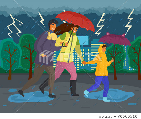 Family walking in the rain with umbrella and wearing raincoats in the city park in autumn season 70660510
