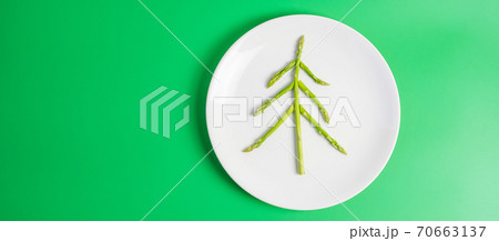 Christmas tree of organic Asparagus with fork and knife on green background. Merry Xmas and happy New Year party, New You, Healthy food and vegetarian concept Christmas tree of organic Asparagus with fork and knife on green background. Merry Xmas and happy New Year party, New You, Healthy food and vegetarian concept 70663137
