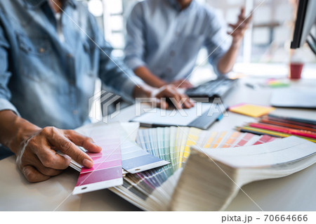 Two colleagues creative graphic designer working on color selection and drawing on graphics tablet at workplace, Color swatch samples chart for selection coloring 70664666