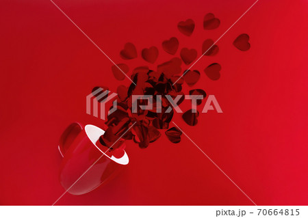 Vibrant red heart-shaped confetti poured out of red cup on red background. Monochrome mockup for your design. Copy space. Flat lay. Vibrant red heart-shaped confetti poured out of red cup on red background. Monochrome mockup for your design. Copy space. Flat lay. 70664815