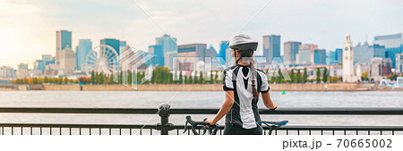 Biking outdoor cyclist on bike path at Old Port of Montreal view cityscape panoramic banner. Woman on bicycle wearing helmet. Summer sports city lifestyle 70665002