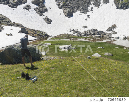 Couple of middle age hikers resting at alpine mountain meadow called Paradies with lush green grass and flowers. Stubai hiking trail, Summer Tyrol Alps, Austria Couple of middle age hikers resting at alpine mountain meadow called Paradies with lush green grass and flowers. Stubai hiking trail, Summer Tyrol Alps, Austria 70665089
