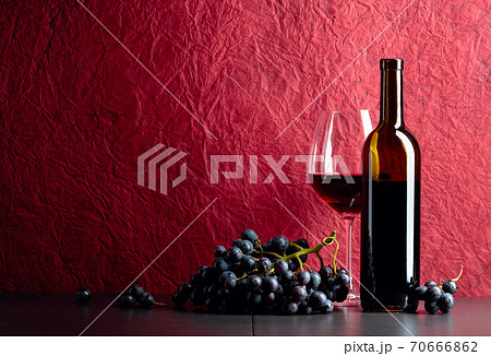 Bottle and glass of red wine on a black table. 70666862