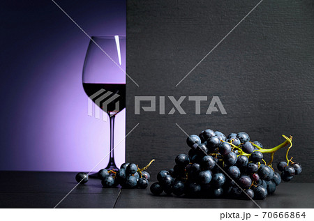 Red wine grapes on a black table and glass of red wine. Red wine grapes on a black table and glass of red wine. 70666864
