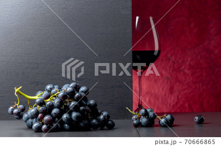 Red wine grapes on a black table and glass of red wine. Red wine grapes on a black table and glass of red wine. 70666865