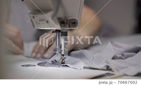 Sewing striped shirt on a white sewing machine close up, female hands Sewing striped shirt on a white sewing machine close up, female hands 70667002