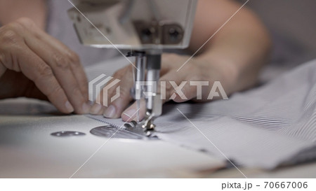 Sewing striped shirt on a white sewing machine close up, female hands Sewing striped shirt on a white sewing machine close up, female hands 70667006