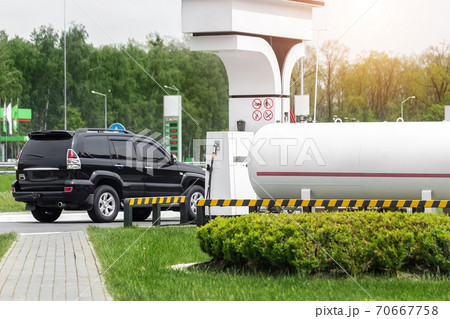 Liquid propane gas station. Black modern SUV car refueling tank with alternative power natural liquefied fuel Liquid propane gas station. Black modern SUV car refueling tank with alternative power natural liquefied fuel 70667758