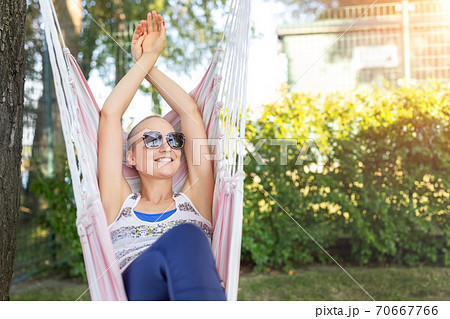 Young adult happy short haired shaved bald attractive woman chilling enjoy relaxing sitting in fabric chair hammock at yard in garden near house. Peaceful and idyllic outdoor rest lifestyle Young adult happy short haired shaved bald attractive woman chilling enjoy relaxing sitting in fabric chair hammock at yard in garden near house. Peaceful and idyllic outdoor rest lifestyle 70667766