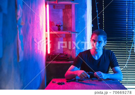 Young man creating dreamcatcher in dark art studio. Young man creating dreamcatcher in dark art studio. 70669278