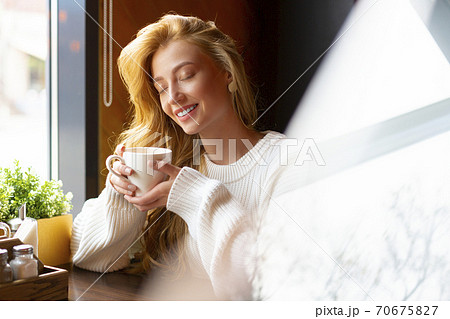 Woman at a cafe drinks tea. Close up portrait. 70675827