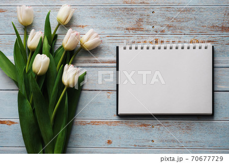 White bouquet of tulips on a wooden blue background with empty notebook 70677729