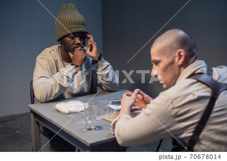 A young black criminal realizes what was done during the interrogation at the police station 70678014