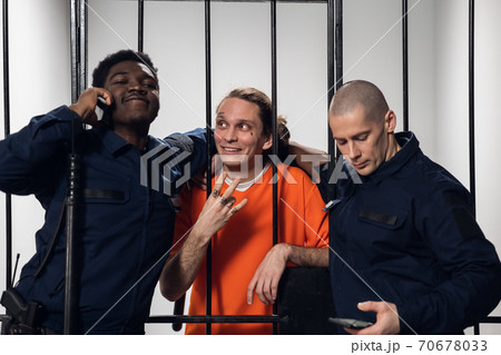 Warders in a high-security prison mock a prisoner in a cell, take photos with him on a smartphone. 70678033